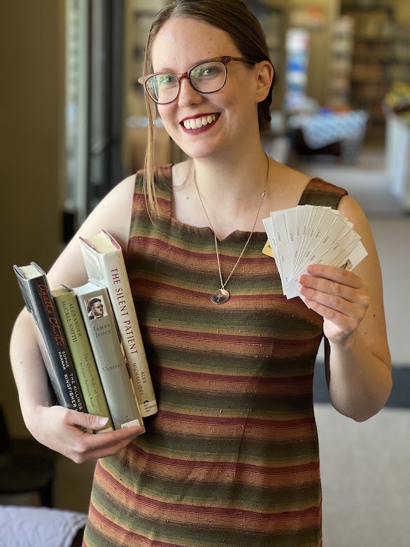 Kiki holds up raffle tickets and books to advertise Summer Reading 2023